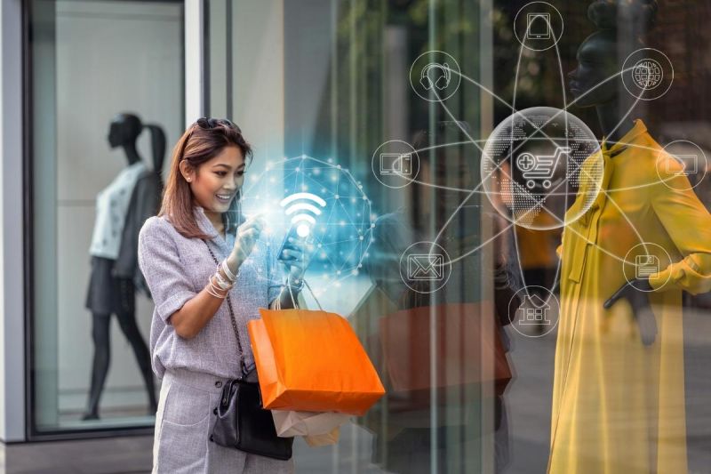 Vrouw die voor een winkel staat en op haar mobiel kijkt