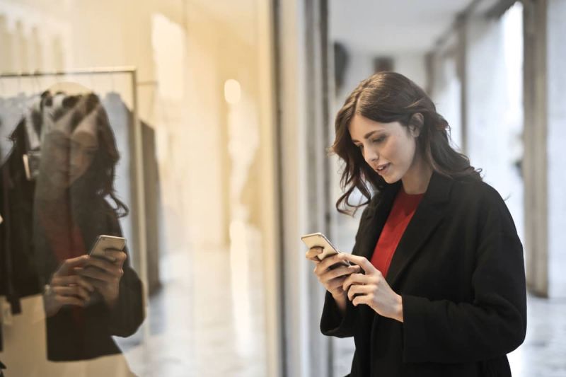 Vrouw winkelt met mobiel in haar hand.