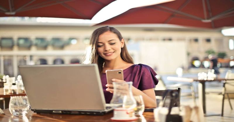 Vrouw achter laptop en telefoon